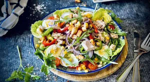Ein bunter, klassischer Thunfischsalat mit knackigem Salat, Ei, Paprika, Mais, Zwiebeln und Croutons.