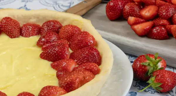 Une délicieuse tarte aux fraises et crème pâtissière, prête à être dégustée. Des fraises fraîches garnissent généreusement cette pâtisserie.