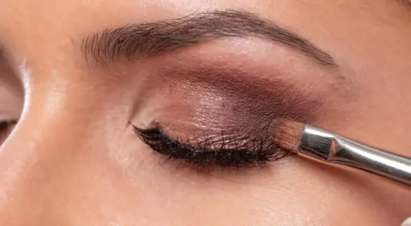 Aplicando sombra marrón con brocha. Aprende como maquillar los ojos a partir de los 50 años para un look elegante y natural.
