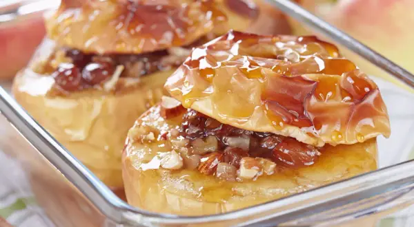 Deux pommes au four dorées, garnies de noix et de raisins secs, nappées d'un sirop brillant. Un délice réconfortant.