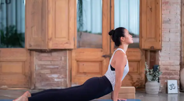 Mujer en postura de cobra, parte de un vinyasa flow yoga que es una secuencia fluida de posturas.