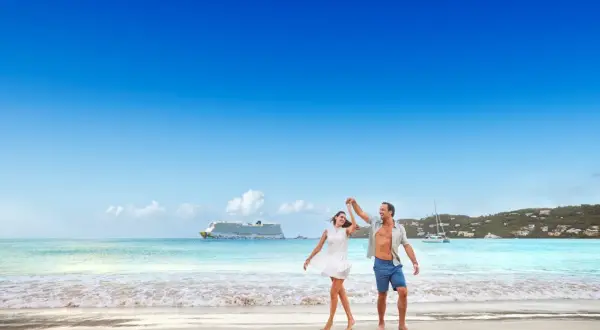 Ett lyckligt par dansar på stranden i San Juan, med ett kryssningsfartyg i bakgrunden.
