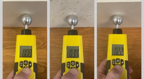Messung der Feuchtigkeit in einer Wand mit einem digitalen Messgerät. Die Werte 0.08, 0.38 und 0.22 zeigen unterschiedliche Feuchtigkeitsgrade an, die für die Wand normalwerte sein können.