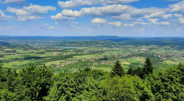 Widok z góry Liwocz na zielone pola, lasy i małe miasteczka pod błękitnym niebem z białymi chmurami.