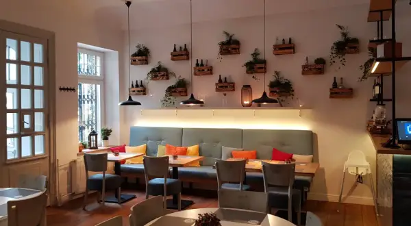 Przytulne wnętrze restauracji Nova Sopot z wygodnymi kanapami, drewnianymi skrzynkami z roślinami na ścianie i stylowymi lampami.