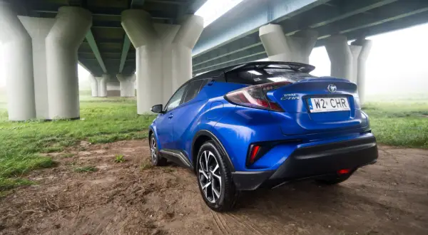 Niebieski Toyota C-HR 2018 zaparkowany pod mostem.