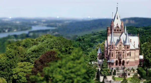 Schloss Drachenburg thront majestätisch inmitten üppiger Wälder, mit Türmchen und Zinnen, die in den Himmel ragen.