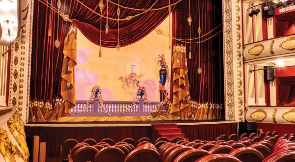 Scena Teatru Wielkiego w Warszawie, bogato zdobiona, z aksamitnymi kotarami i malowidłem przedstawiającym anioły.