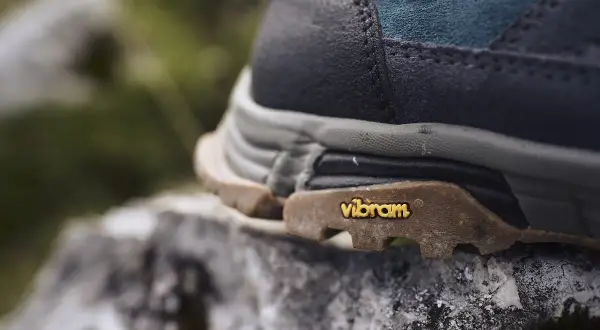 Nahaufnahme eines Wanderschuhs mit Vibram-Sohle auf einem Stein. Mögliche vibram sohle nachteile wie Abnutzung sind hier nicht sichtbar.