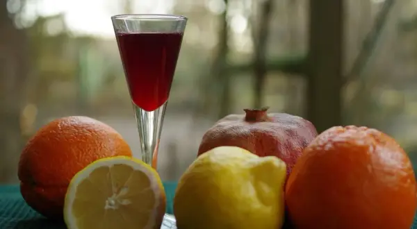 Szklanka z czerwonym płynem, obok pomarańcze, cytryna i granat. Czy to grenadyna? Hajduczek naturalnie.