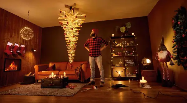 Mann steht vor umgedrehtem Holz-Weihnachtsbaum mit Lichtern. Tolle alternativen zum Weihnachtsbaum für ein modernes Zuhause.