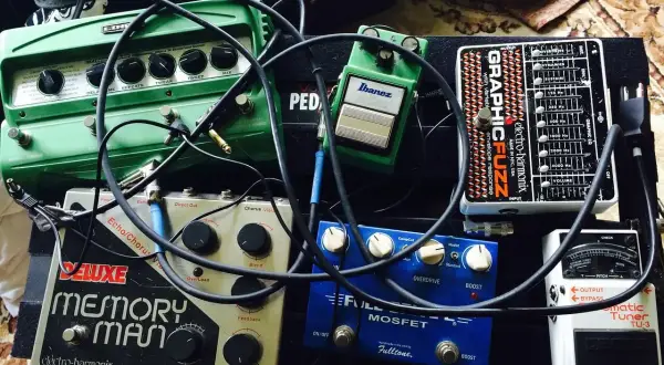 Pedalboard z efektami gitarowymi: zielony delay, srebrny Memory Man, niebieski Fulltone, czarny Electro-Harmonix i biały tuner.