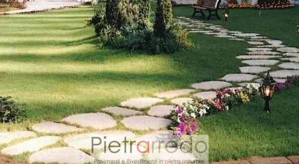 Un sentiero sinuoso di pietre irregolari attraversa un prato verde, creando un passaggio suggestivo nel giardino.
