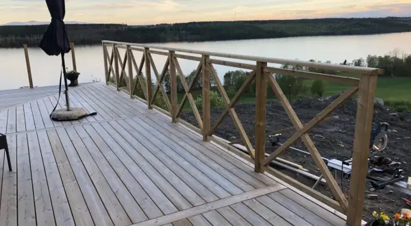 Nybyggd altan med räcke av skarva reglar. Vacker utsikt över sjö och skog.