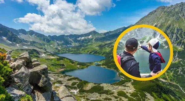 Ojciec i dziecko na szlaku w Dolinie 5 Stawów. Chłopiec wskazuje na jezioro, podziwiając górski krajobraz.