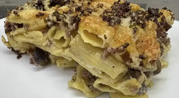 Un invitante piatto di pasta al forno, la ricetta della nonna, con pasta rigata, ragù e formaggio filante.