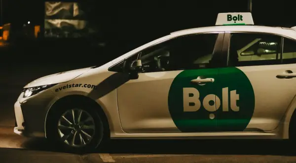 Biały samochód z zielonym logo Bolt na drzwiach i na dachu. To auto do pracy w Bolt.