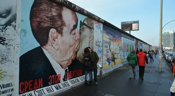 East Side Gallery Berlin: para zakochanych całuje się na tle słynnego malowidła "Braterki" Breżniewa i Honeckera.