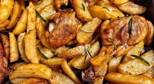 Fusi di pollo al forno con patate dorate e rosmarino, un piatto succulento e profumato, pronto per essere gustato.