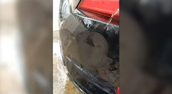 Usuwanie wgnieceń gorącą wodą na czarnym zderzaku samochodu. Woda spływa po uszkodzonym fragmencie.