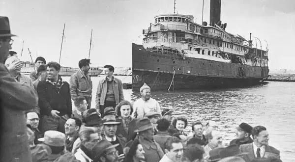 Folk samlas vid en skadad båt, en scen som speglar en del av israel historia.