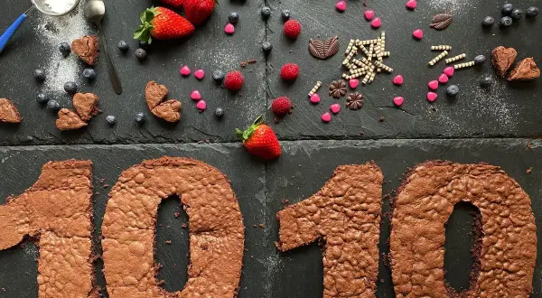 Zahlentorte mit Biskuitboden in Form einer 10, dekoriert mit Erdbeeren, Blaubeeren und Schokoladenherzen.