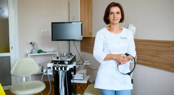 Lekarka w gabinecie foniatrycznym, z aparaturą medyczną w tle. Czy badanie u foniatry jest bolesne? Niekoniecznie, nowoczesny sprzęt i doświadczenie lekarza minimalizują dyskomfort.