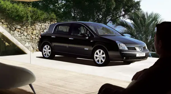 Czarny Renault Vel Satis zaparkowany na tarasie z widokiem na morze. Mężczyzna siedzi w fotelu, podziwiając auto.