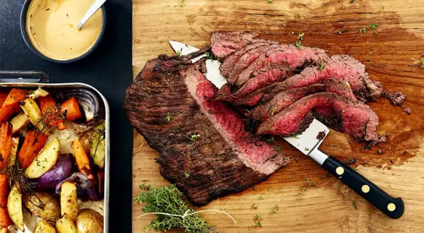 Saftig flankstek i ugn, skivad och serverad med ugnsrostade rotfrukter och en krämig sås.