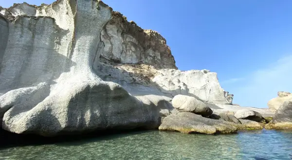 Impresionante costa amarga con formaciones rocosas blancas y agua cristalina bajo un cielo azul.