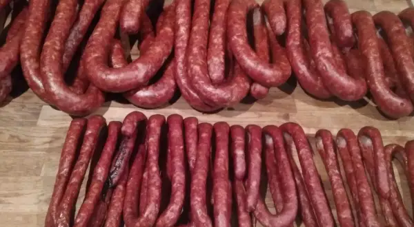 Prawdziwa wiejska kiełbasa przepis: wędzone, suszone pęta na drewnianym blacie.