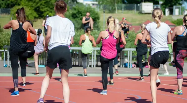 Grupa kobiet ćwiczy na świeżym powietrzu. Zastanawiasz się, ile kcal to kilogram? Ta aktywność spala kalorie, pomagając osiągnąć cel.