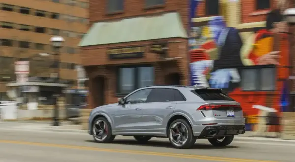Srebrny Audi RS Q8 pędzi ulicą obok kolorowego muralu. Sprawdź aktualną audi rsq8 cena i możliwości tego SUV-a.
