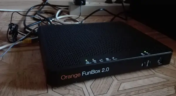 Czarny router Orange FunBox 2.0 z wieloma kablami podłączonymi do listwy zasilającej.