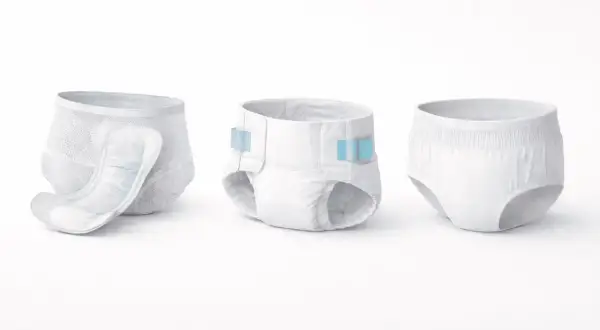 Drei verschiedene Arten von Windeln und Pflegehilfsmitteln: eine mit Einlage, eine mit Klebestreifen und eine als Slip.