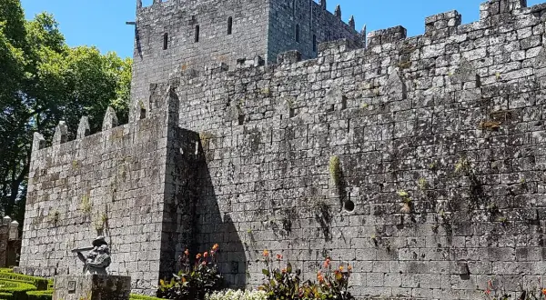 El imponente castillo de Sotomayor se alza sobre un jardín cuidado, con sus muros de piedra y almenas bajo un cielo azul.