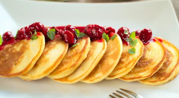 Złociste placuszki, idealne na śniadanie, polane wiśniowym sosem i udekorowane listkami mięty. Pyszny przepis na pancake!