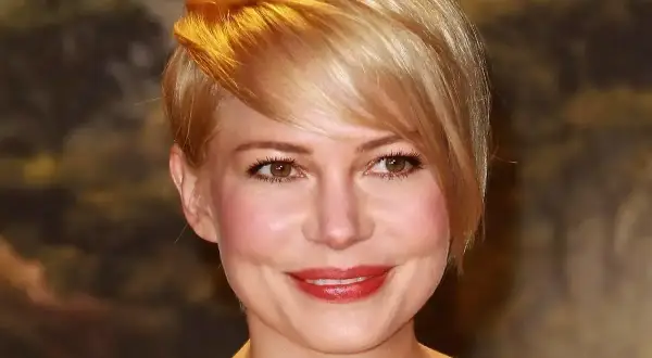 Kobieta z okrągłą twarzą i stylową, krótką fryzurą w odcieniu blondu.