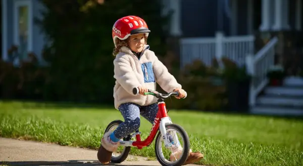 Kleines Kind mit Helm fährt Laufrad. Die richtige Einstellung des Laufrads ist wichtig für den Fahrspaß.