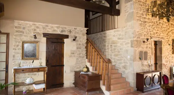 Interior de una casa antigua con paredes de piedra, vigas de madera y una escalera. Un proyecto de reformar casa antigua que conserva su encanto rústico.