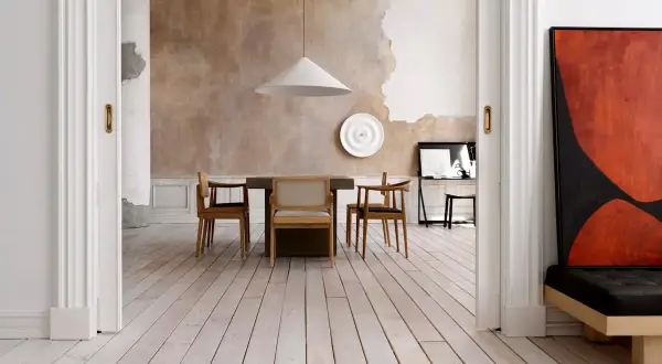 Sala da pranzo con pareti a pittura a calce grezza, tavolo in legno e sedie moderne. Un quadro astratto rosso e nero domina lo spazio.