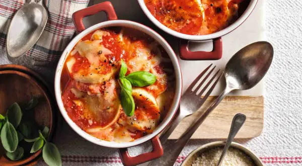 Gnocchi alla Romana ricetta della nonna: dischi dorati al forno, ricoperti di sugo di pomodoro e formaggio filante, guarniti con basilico fresco.