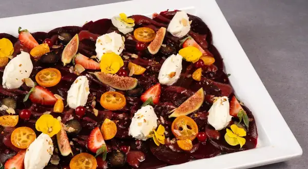 Eleganckie carpaccio z buraka z kawałkami fig, truskawek, kumkwatów, serka i jadalnych kwiatów.