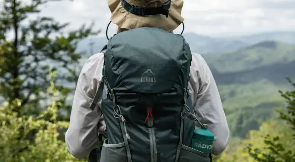 Osoba w kapeluszu z plecakiem Elbrus Moonhill 30 podziwia górski krajobraz.