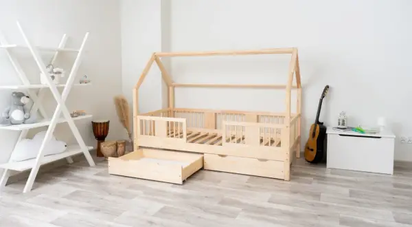 Łóżko domek z litego drewna sosnowego, z szufladami, obok regał, bębny i gitara.