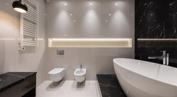 Baño moderno con bañera exenta, inodoro, bidet y toallero. Iluminación indirecta crea un ambiente chill out.