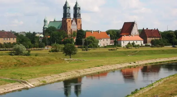 Widok na Ostrów Tumski w Poznaniu z katedrą i innymi zabytkowymi budynkami nad rzeką Wartą.