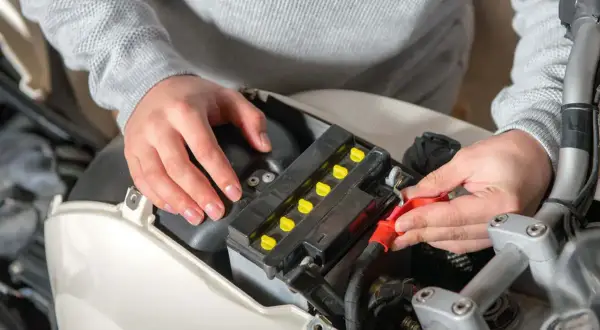 Persona revisando el voltaje de la batería de una moto.