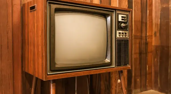 Stary telewizor z drewnianą obudową i ekranem kineskopowym. Ciekawe, w którym roku powstał pierwszy telewizor, bo ten wygląda na prawdziwy antyk.