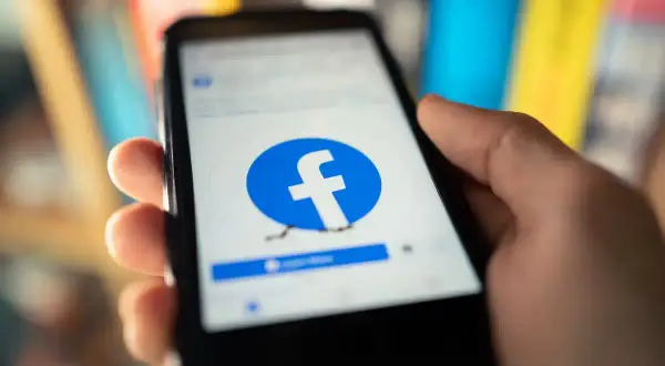 Dłoń trzyma smartfon z logo Facebooka. Chcesz wiedzieć, jak usunąć fb ale zostawić messengera?